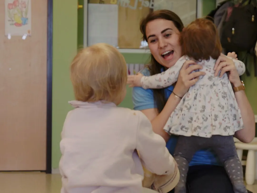 Kinderbetreuerin spielt mit Kleinkindern im Kinderbereich des Fitnessland